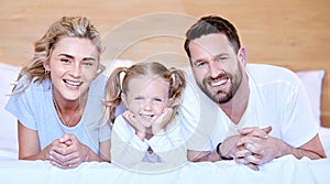 Portrait of happy carefree caucasian family lying cosy on bed while bonding together at home. Loving parents spending