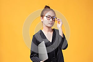 Portrait of happy casual Asian girl student with laptop isolated on yellow background. Back to school and learning concept