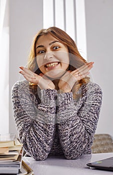 Portrait of a happy casual businesswoman in sweater sitting at her workplace in office