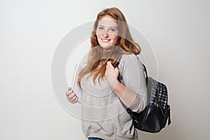 Portrait of happy casual woman with backpack against white studio wall background