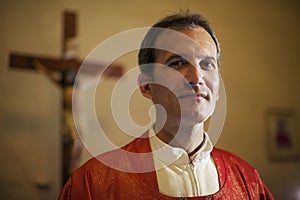 Portrait of happy catholic priest smiling at camera in church