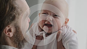 Portrait of happy caucasian baby girl newborn carefree child smiles enjoys family time. Back view bearded father holding