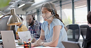 Portrait of happy caucasian businesswoman talking on phone headset at office