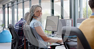 Portrait of happy caucasian businesswoman talking on phone headset at office