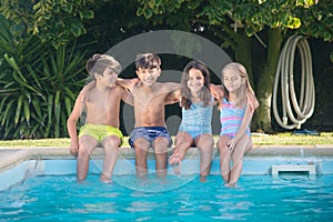 Portrait of happy Caucasian children wetting their legs in pool