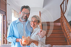 Portrait of happy caucasian couple holding piggy bank to save money to make their future dreams come true. Loving man and woman