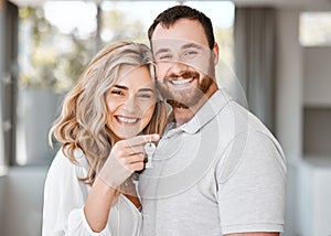 Portrait of happy caucasian couple holding up house keys. Affectionate couple looking happy after buying their first or