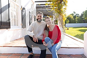 Portrait of happy caucasian couple sitting on terrace in garden, smiling to camera