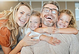 Portrait of a happy Caucasian family of four relaxing in the living room at home. Loving smiling family being