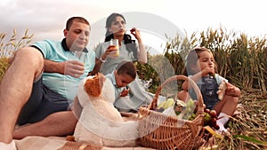 Portrait of a happy caucasian family with two kids having a picnic in a wheat field in slowmo