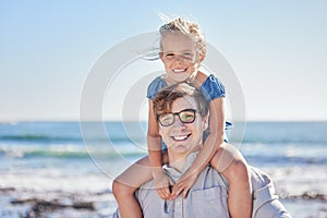 Portrait of happy caucasian father with glasses carrying his daughter on his shoulders at the beach on a sunny day