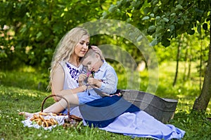 Portrait of Happy Caucasian Mother With Her Upset Little Kid. Posing with Basket Full of Bread Rings Outdoors