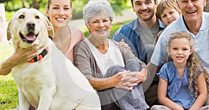 Portrait of happy caucasian multi generation family sitting with pet dog in park