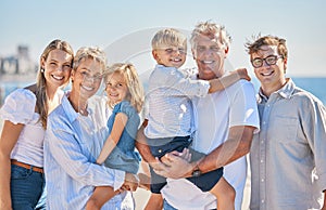Portrait of happy caucasian multi-generation family standing together at the beach on a sunny day. Two little children