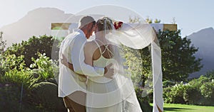 Portrait of happy caucasian newly wed couple, dancing in front of altar outdoors