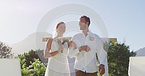 Portrait of happy caucasian newly wed couple, walking down the altar outdoors