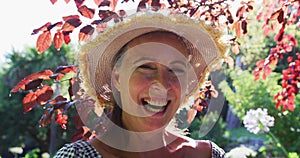 Portrait of happy caucasian senior woman in garden wearing sunhat and smiling in the sun