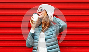 Portrait happy caucasian smiling young woman with cup of coffee posing wearing a white hat on red background