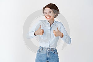 Portrait of happy caucasian woman show thumbs up and smile in approval, praise good job, well done gesture, like and