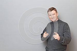 Portrait of happy charismatic man pointing with index fingers at you