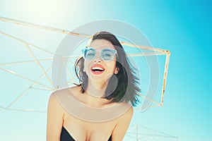 Portrait of happy cheerful emotional young woman in trendy glasses laughing enjoying summer on the beach. Holidays Vacation