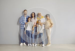 Portrait of a happy, cheerful family standing all together by the wall in the studio
