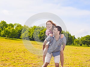 Portrait of Happy and Cheerful Young Caucasian Couple Piggybacking Outdoors.Summer Vacations and Youth Lifestyle Concept. Against