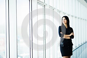 Attractive smiling young business woman. Portrait of happy cheerful young lady with crossed arms on business center window backgro