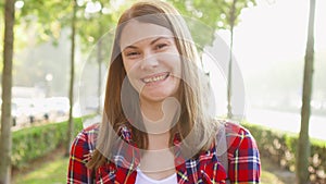 Portrait of happy cheerful young woman enjoying nature. Walking in green park smiling at camera