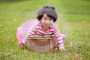 Portrait, happy child and basket for picnic in park with laugh, smile and fun. Girl. curly hair and natural in pink tutu