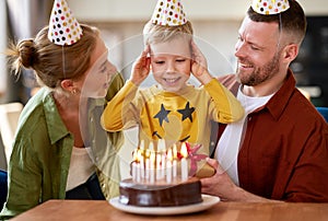 Portrait of happy child boy celebrating birthday with young parents at home