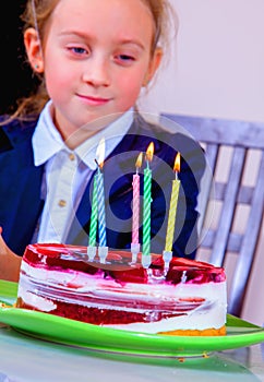 Portrait of happy child girl with cake and candle celebrating birthday. Holiday, happiness, joy and childhood concept. Selective