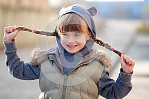 Portrait of happy child girl with hair braids in warm clothes in autumn outdoors