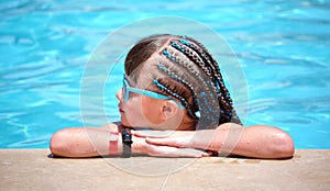 Portrait of happy child girl relaxing on swimming pool side on sunny summer day during tropical holidays