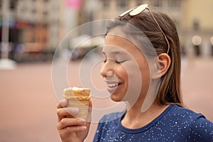 Portrait of a happy child with ice cream in hands on a city street.