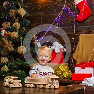 Portrait of happy child looking at decorative toy ball by Christmas tree. Kid enjoy the holiday. Happy little child
