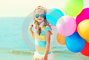 Portrait happy child on summer beach with colorful balloons