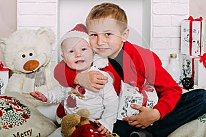 Portrait of happy children with Christmas gift boxes and decorations. Two kids having fun at home