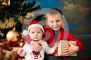 Portrait of happy children with Christmas gift boxes and decorations. Two kids having fun at home