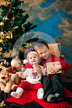 Portrait of happy children with Christmas gift boxes and decorations. Two kids having fun at home