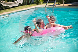 Portrait of happy children with inflatable ring in pool