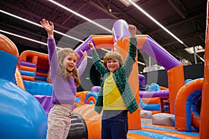 Portrait of happy children with raised hands up playing in bounce house