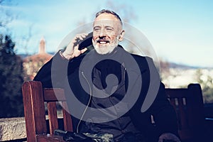 Portrait of happy confident businessman with his smartphone while sitting in city park.Horizontal ,blurred background.