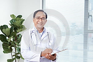 Portrait of happy confident doctor holding file in hospital corridor