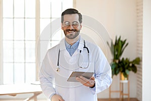 Portrait of happy confident young male doctor with tablet pc