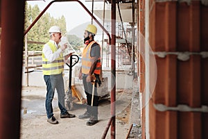 Portrait Of Happy Construction Site Supervisor Talking To Manual Worker