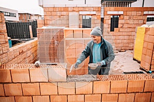 Portrait of happy construction worker building walls, mason building house