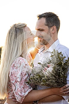 Portrait of a happy couple with a bouquet during a warm sunset