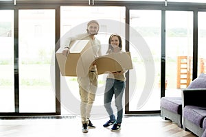 Portrait of happy couple carrying boxes moving into new house