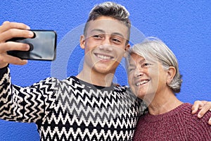 Portrait of a happy couple of grandmother and teenage grandson smiling and hugging each other looking at the mobile phone for a